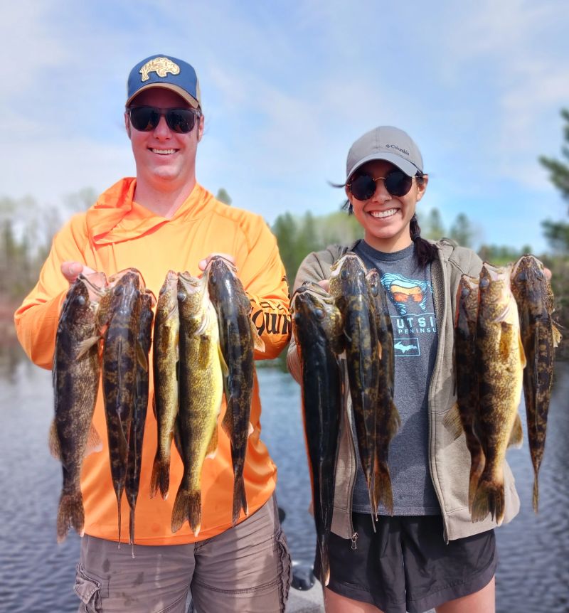Two anglers each holding walleye caught on the same drift