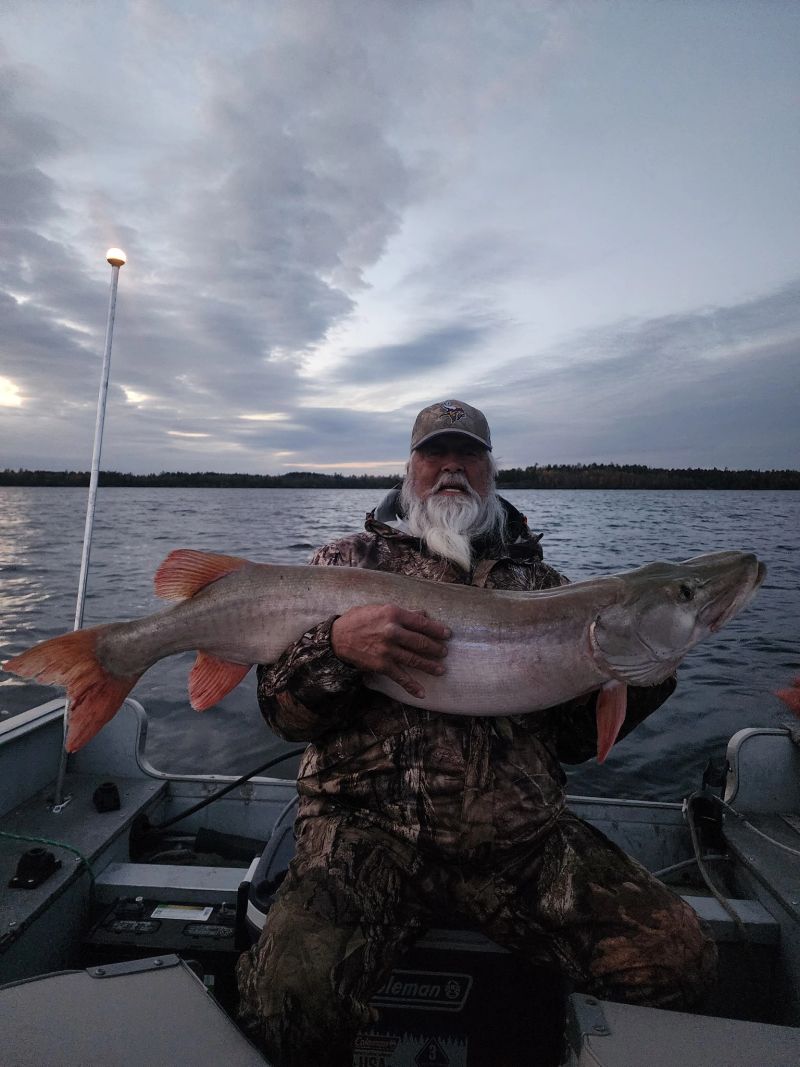 Angler holding a muskie under a wide northern Minnesota sky