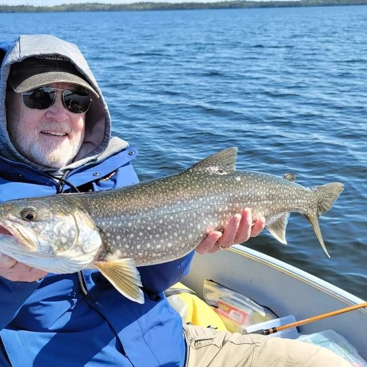 Angler holding a lake trout beside deep blue water