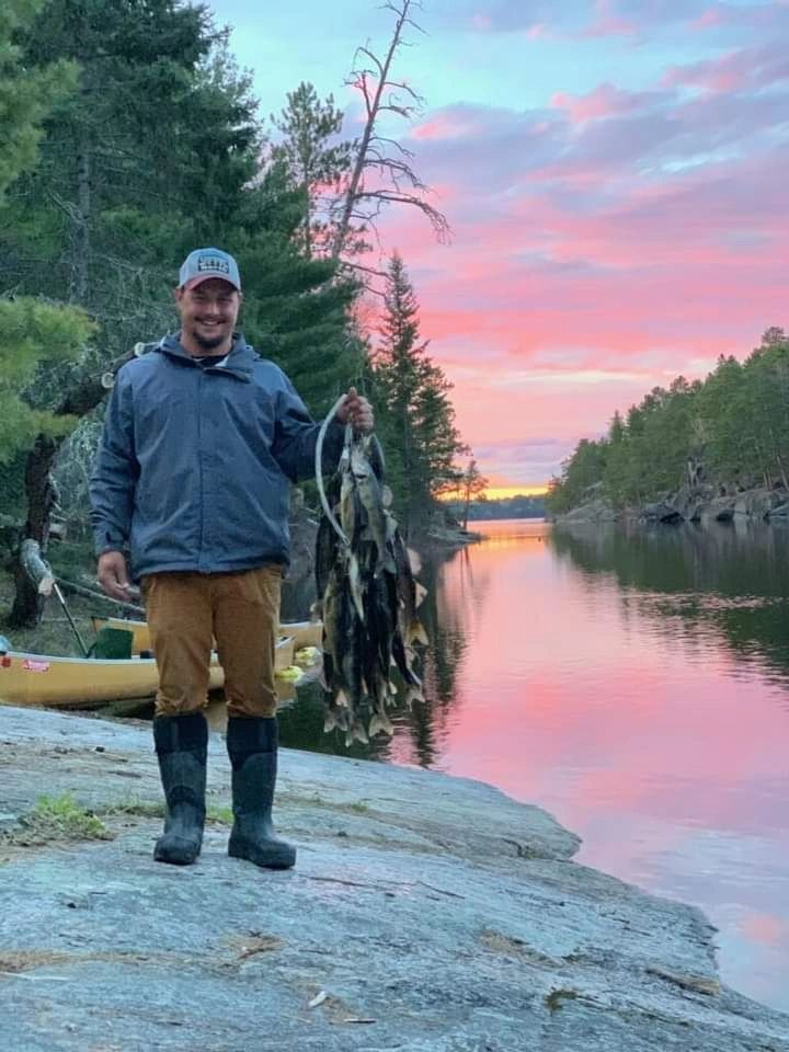 Angler beside a canoe at sunset in the Boundary Waters
