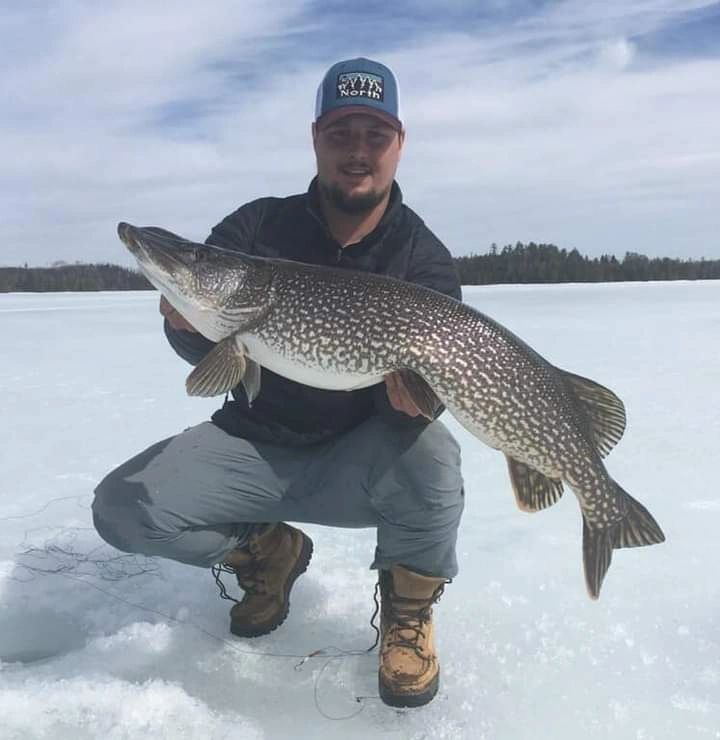 Ice angler with a giant northern pike on a frozen Ely lake