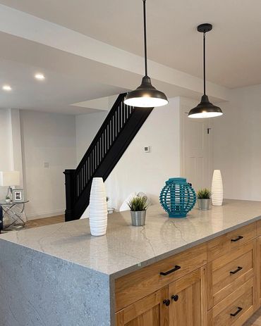 Large farmhouse style island with waterfall countertops, Black restored staircase and black lights  
