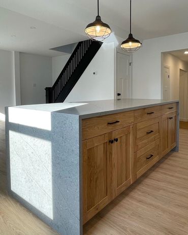 Large farmhouse style island with waterfall countertops, Black restored staircase and black lights  