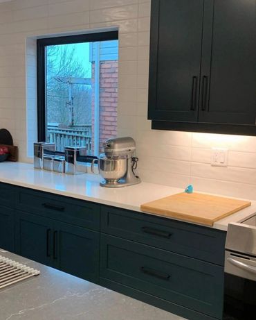 Very rich looking dark green kitchen with large window at counter height. Undercabinet lighting 
