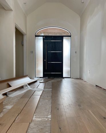Oversized front door with arched window above. Engineered flooring being installed.