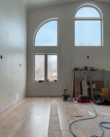 Living room construction in progress, engineered hardwood flooring being installed, gas fire place 