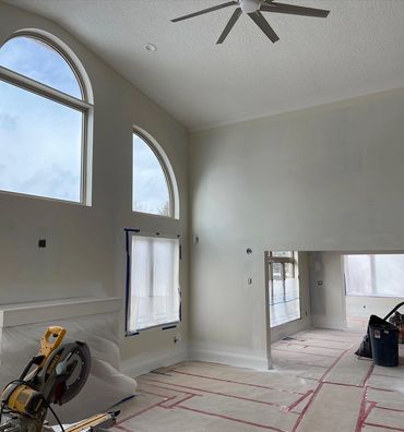Large living room with arched windows, high ceilings. New hardwood laid and protected.