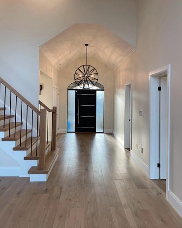 Beautiful front foyer with natural oak hardwood and a custom stair case, with a black iron light