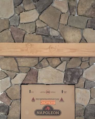 Natural wood mantel, over a Napoleon gas fire place. Surrounded by a beautiful field stone veneer 