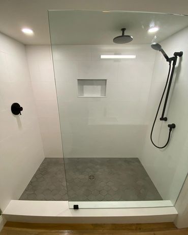 Basement bathroom, with custom shower glass and bamboo wallpaper. Lvp flooring and black hardware 