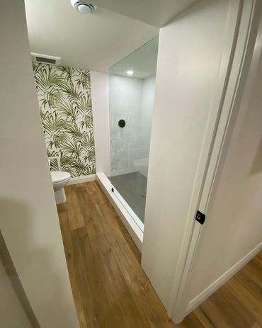 Basement bathroom, with custom shower glass and bamboo wallpaper. Lvp flooring and black hardware 