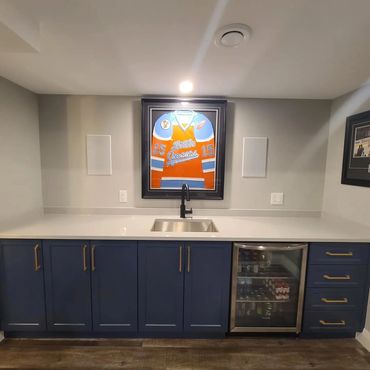 Basement reno with a sporty bar, blue cabinets and quartz counter tops 