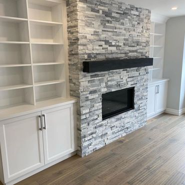 Gas  fireplace with stacked stone veneer, custom wood mantel and custom built ins on either side 