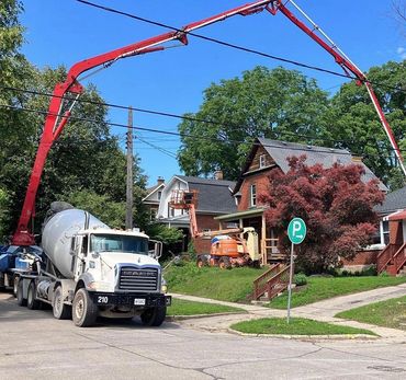 Concrete pump and truck, pumping concrete over the existing home for a large backyard addition 