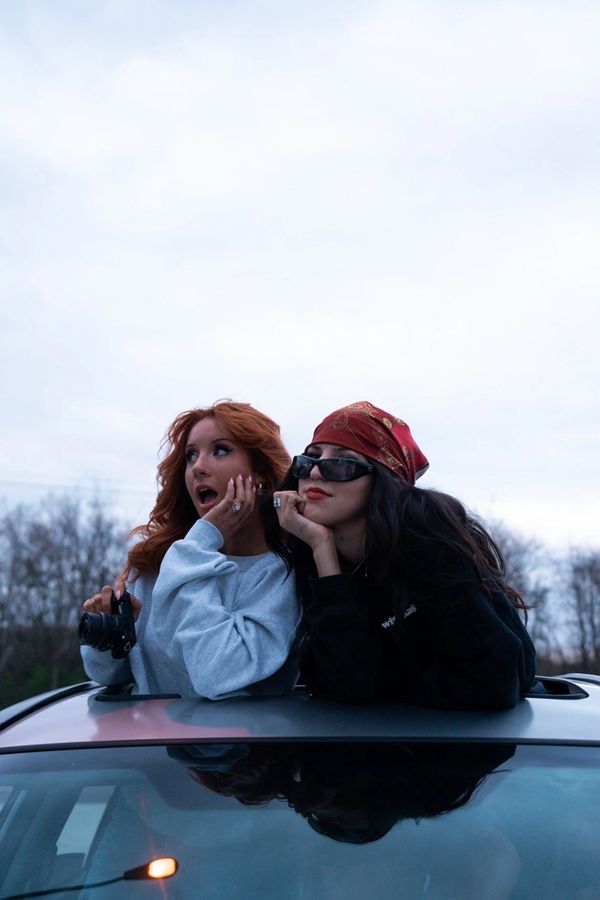 two girls on top of a car sun roof