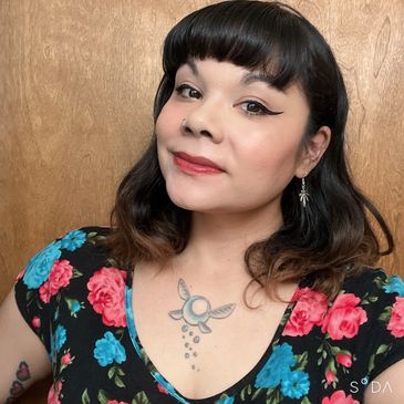 Woman with floral dress and fairy tattoo on chest.
