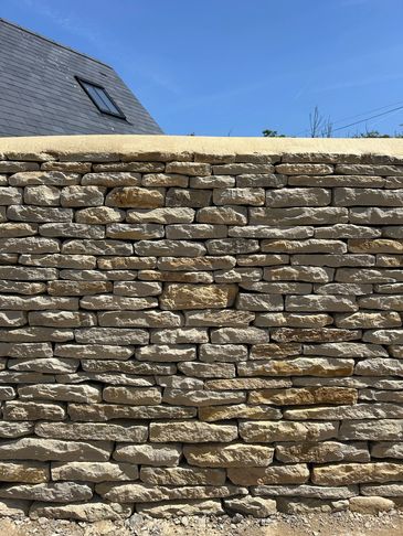 Close-up of a stone wall under a clear blue sky.