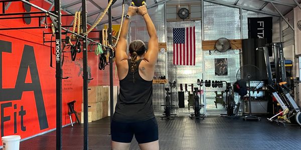 Female member of Alta CrossFit doing a kettlebell swing during a workout