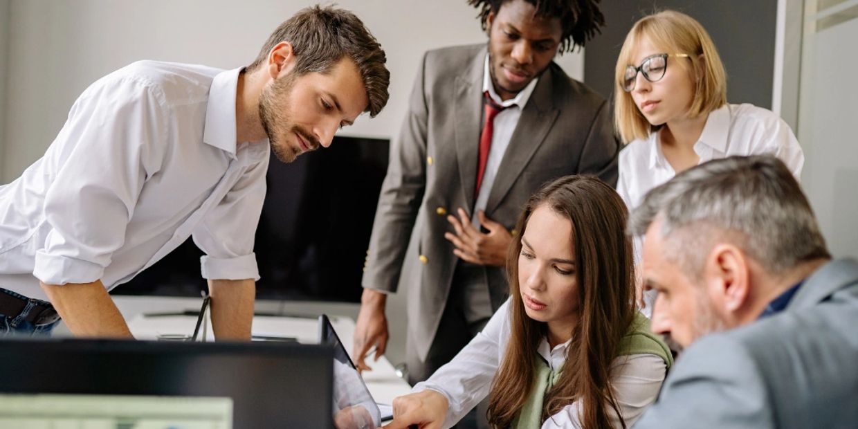 Five professionals in a meeting focused on work.