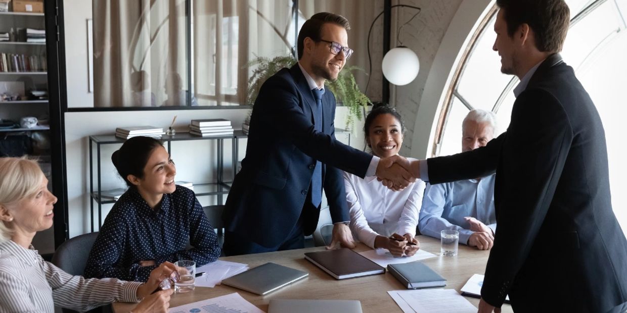 Businessmen shaking hands in a meeting room.