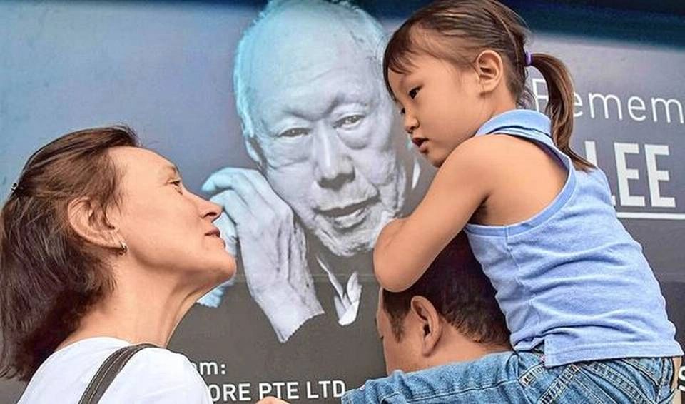 “Lee Kuan Yew declared that Singapore would become the first ‘developed’ country in Asia.” A family is seen in front of a memorial portrait of Lee outside the parliament building ahead of his funeral in 2015. AFP
