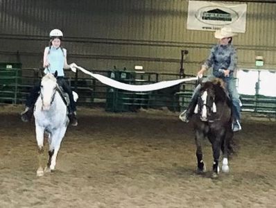 2 riders holding a length of toilet paper between them, trying not to break it, in a  games class.