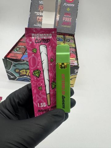 Hand holding a green vape pen and pink Diamond Coated packaging.