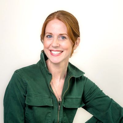 Smiling woman with red hair wearing a green jacket.