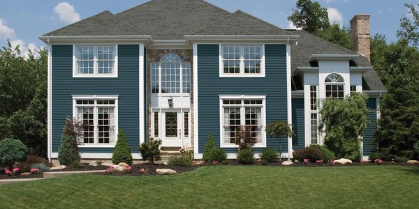 Large blue two-story house with white trim and a well-kept lawn.