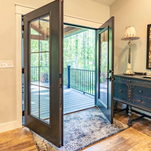 Open double doors lead to a wooden porch with forest views.