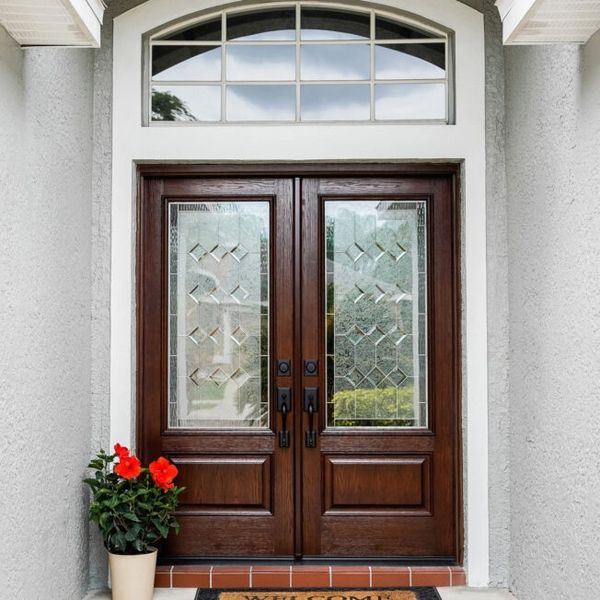 Elegant wooden double doors with decorative glass panels and a welcome mat.