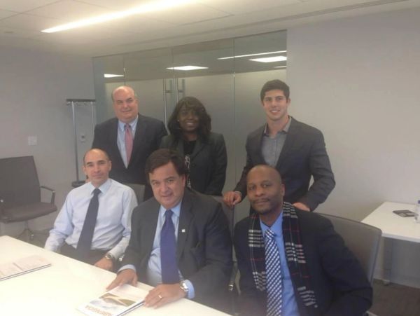 Six professionals posing in a modern office meeting room.