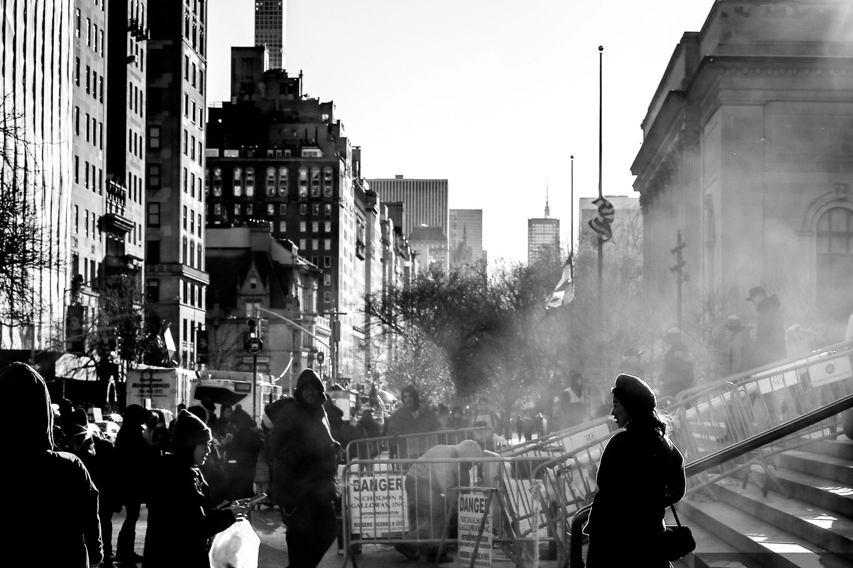 Black and white city street scene with dramatic shadows and people walking.