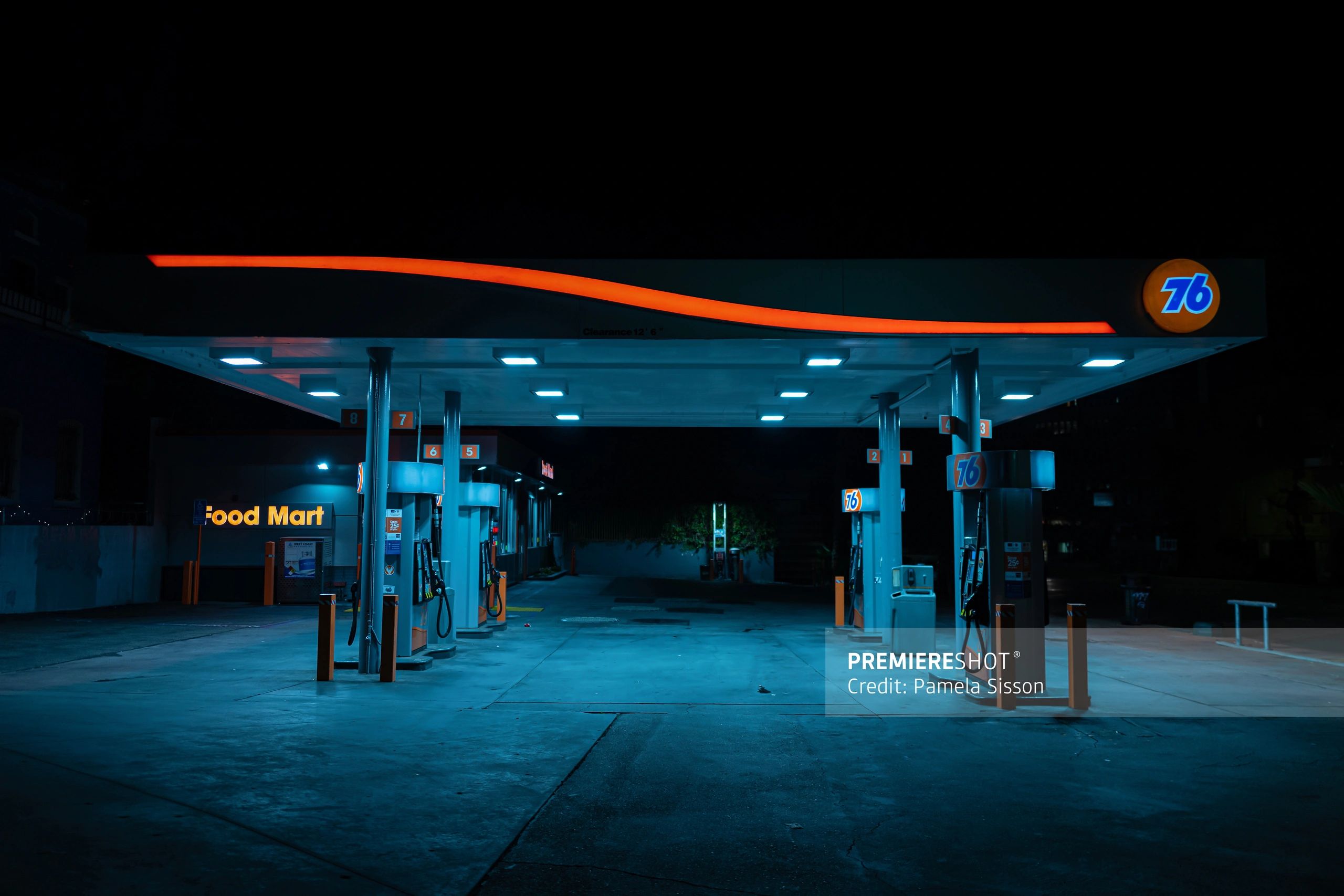 Empty 76 gas station at night with bright neon lighting.