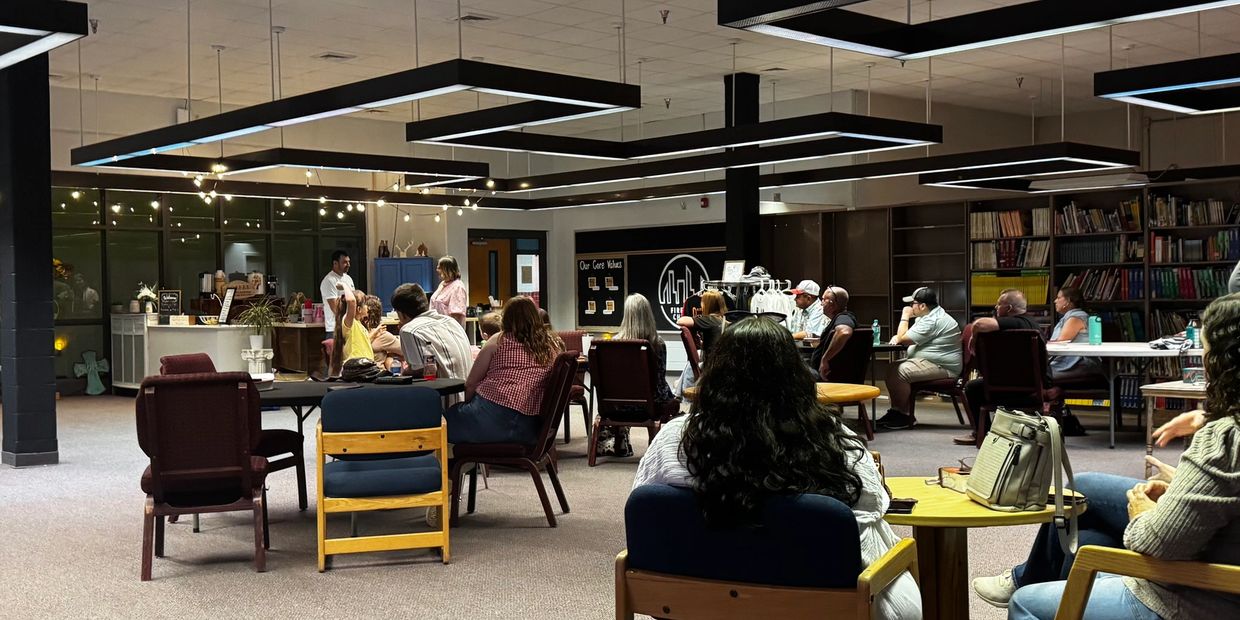 People gathered in a meeting room with bookshelves and modern lighting.
