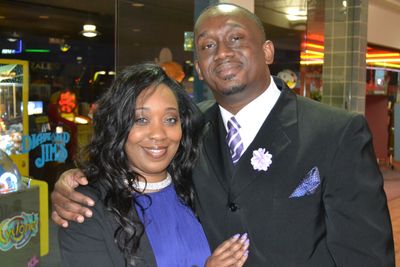 A smiling couple dressed formally at an indoor event.