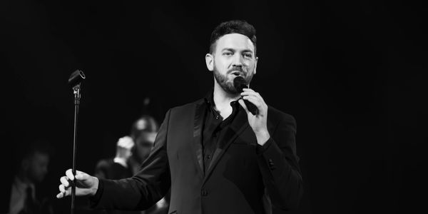 Man singing on stage with microphone.