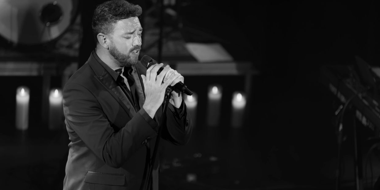 Man singing passionately into a microphone on stage.