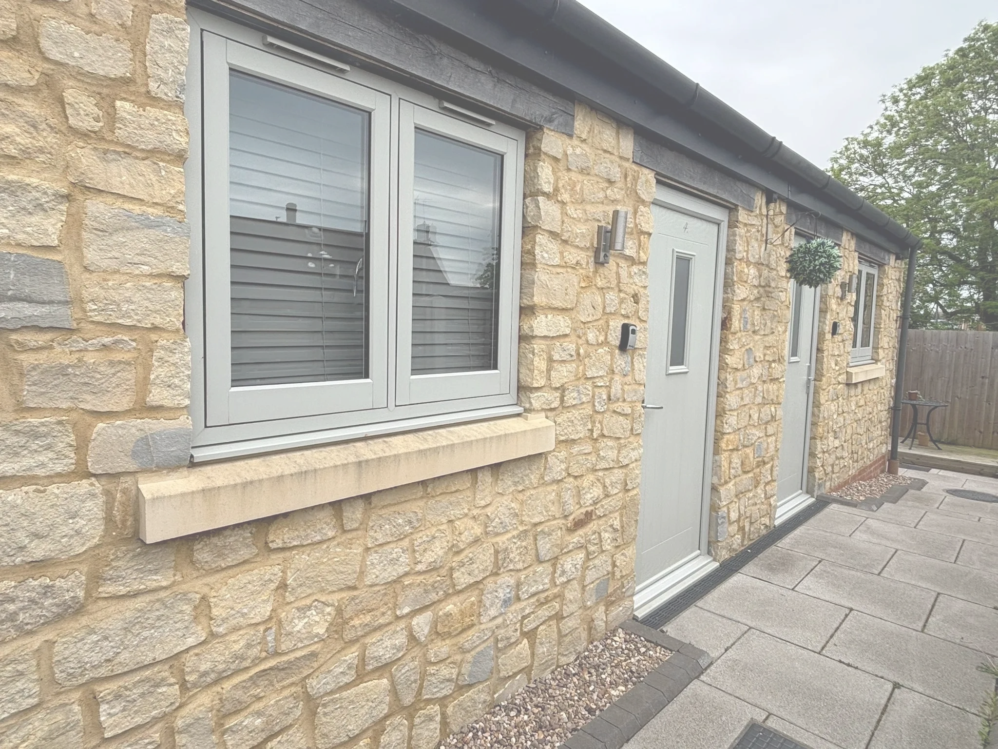 Stone house exterior with grey windows and doors.