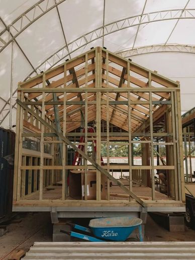 Wooden frame structure of a building under construction inside a tent.