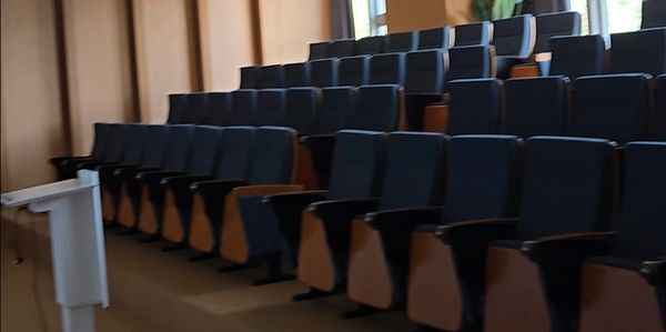 Empty lecture hall with rows of seating and a podium.