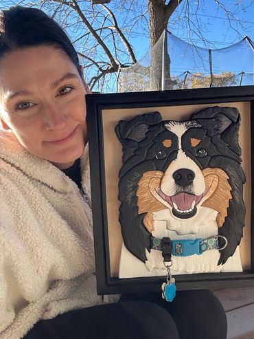 Woman posing with a framed dog portrait.