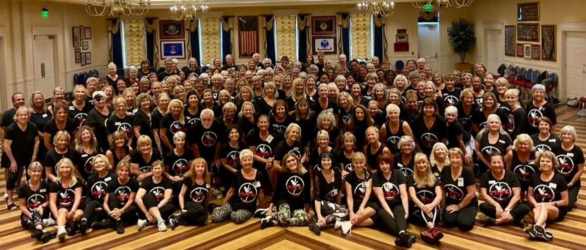 Large group of people wearing matching black shirts posing indoors.