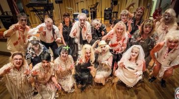 Group of people dressed as zombies in theatrical setting.