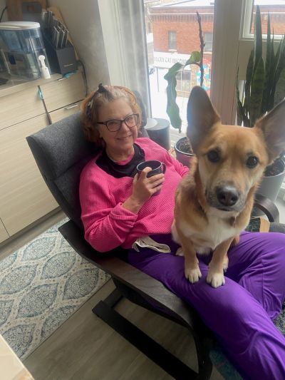 Woman in pink sweater sitting with a dog on her lap.