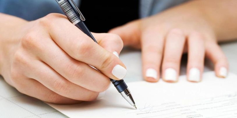 Person writing with a pen on a document.