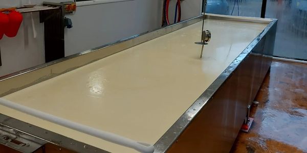 Large vat filled with creamy liquid, likely cheese or dairy processing.