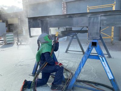 Our team of sandblasters removing coating from a loading ramp.