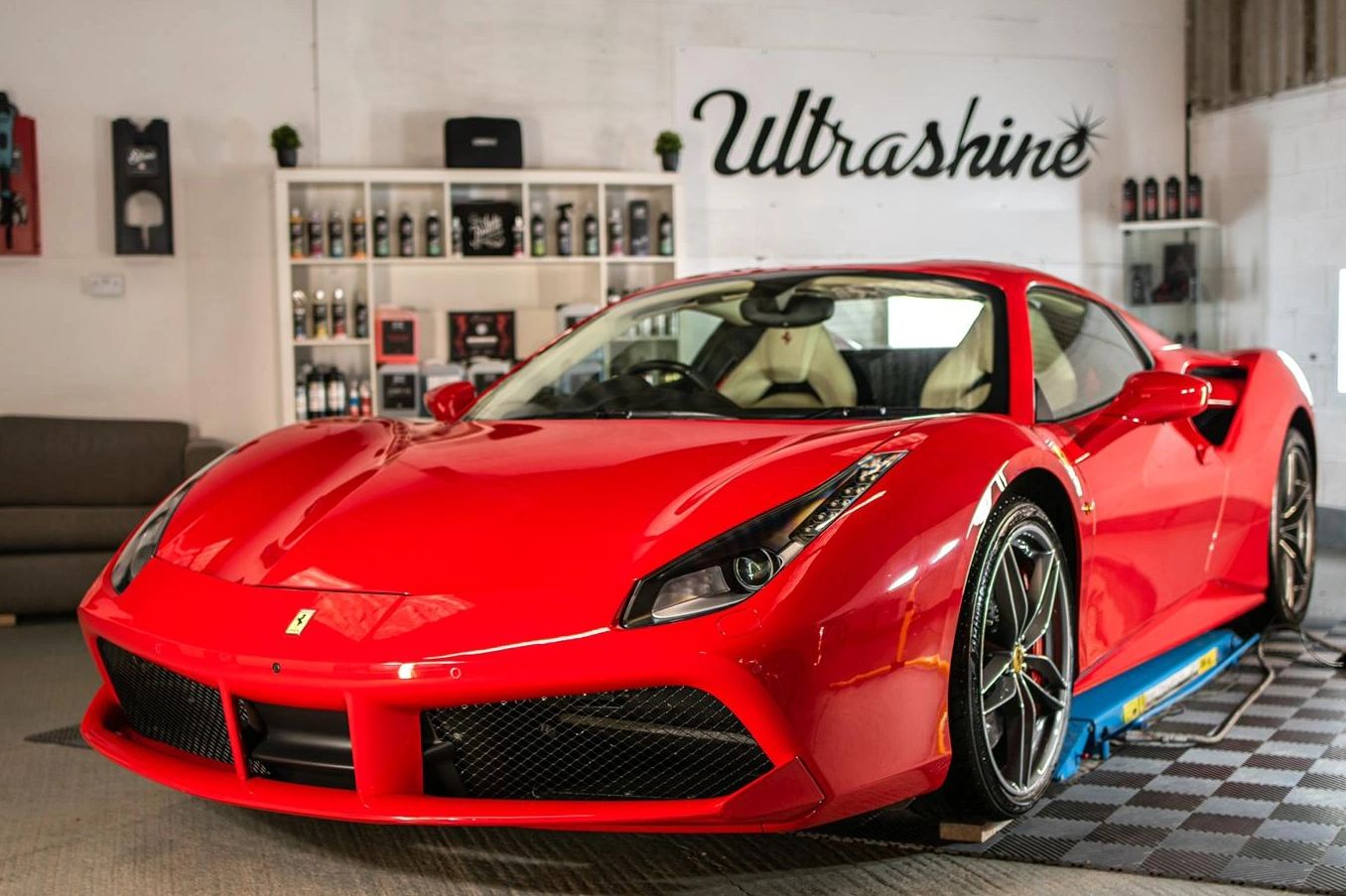 A shiny red Ferrari sports car in a garage with Ultrashine branding.
