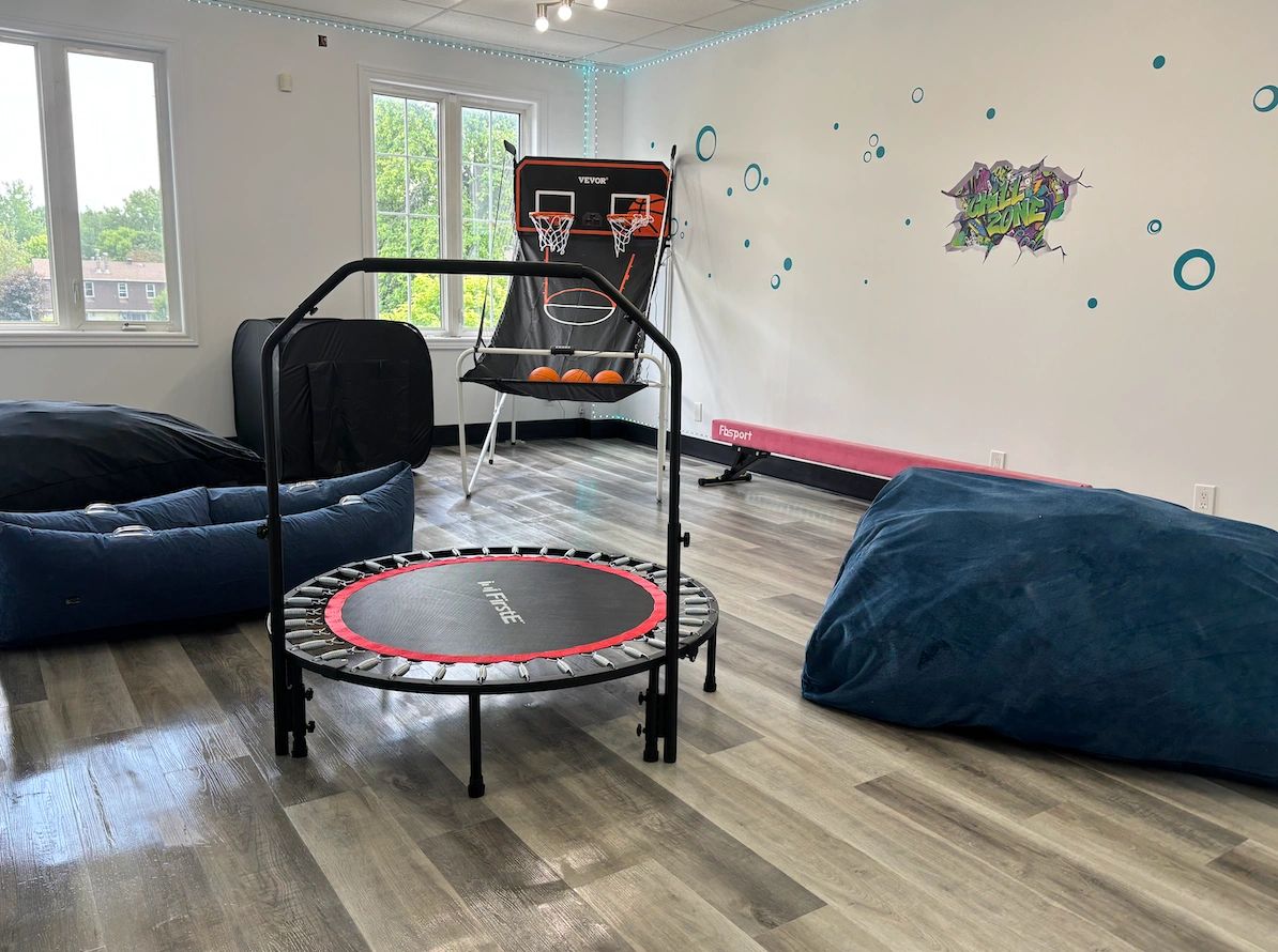 Indoor playroom with trampoline, basketball game, and bean bags.